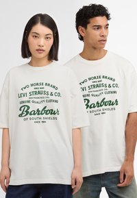 Valged puuvillased t-särgid lühikeste varrukatega, mille esiküljel on rohelise trükitud tekst ja logod Levi Strauss & Co. ja Barbour.