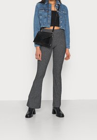 Krótka kurtka jeansowa, czarny krótki top, szare rozszerzane spodnie z teksturą oraz czarne buty na obcasie. Czarna torebka na ramię z wzorem krokodyla.