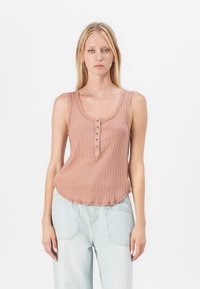 Lichtroze geribde tanktop met een ronde halslijn, knopenlijst en een gebogen zoom. Draag het met lichtblauwe wijde jeans.