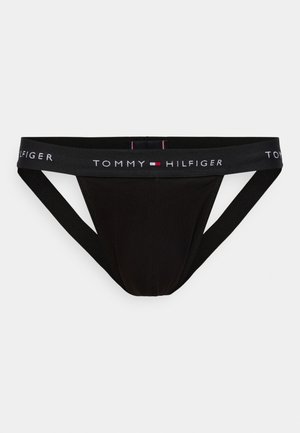 Melns vīriešu tangi no kokvilnas maisījuma ar elastīgu jostu, kurā redzams "TOMMY HILFIGER" logotips baltā krāsā ar sarkaniem akcentiem. Minimālistisks dizains.