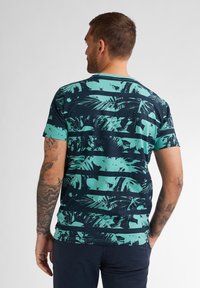 Moška kratkosleeve majica v mornarsko modri barvi s turkiznim tropskim listnatim vzorcem. Narejena iz mehkih materialov, ima okroglo izrezovanje in običajen kroj.