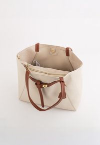 Beige læder tote bag med to brune håndtag og guld hardware. Åben top afslører en tan inderside og et lynlåslomme.