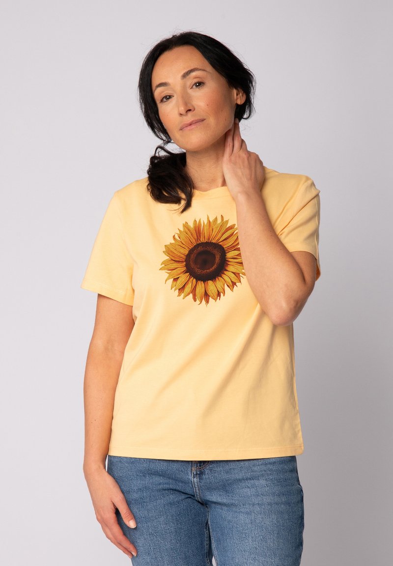 Lichtgele katoenen t-shirt met een zonnebloemafbeelding in tinten geel en bruin, korte mouwen en een relaxte pasvorm.