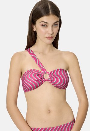 Joven mujer con un top de bikini de un solo hombro a rayas en rosa, verde y blanco, con un detalle de anillo central, posando contra un fondo liso.