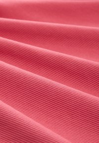 Tissu rose à côtes avec une texture lisse, présentant des lignes horizontales uniformément espacées, plié en douces vagues.