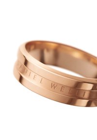 Rose gold rengas, jossa on sileä, kiillotettu pinta. Siinä on kaiverrettua tekstiä ja kaksi hieman sivussa olevaa rengasta, jotka luovat kerroksellisen ilmeen.