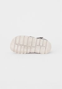 Sneakersula i ljusgrå gummi, med texturerade spår och kanter för grepp. Ren, minimalistisk design utan synlig varumärkning.