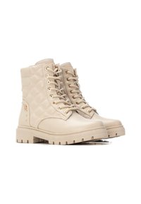 Botas de combate beige con un diseño acolchado, ojales dorados y suelas de goma gruesas. Presenta acentos texturizados y detalles de tachuelas en el costado.