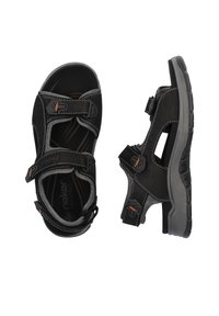 Sandale noire avec des sangles Velcro réglables, semelle en caoutchouc texturé et couture blanche contrastante. Conçue pour le confort et la durabilité.