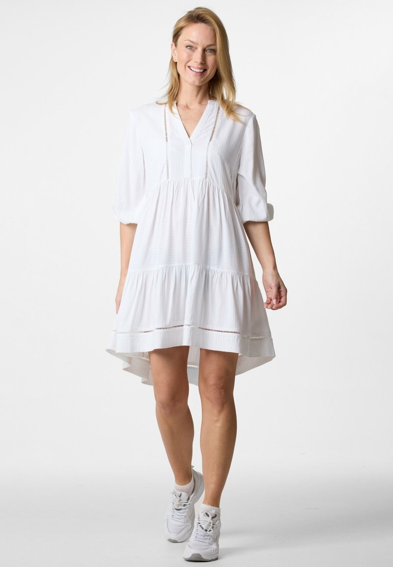 Weißes, knielanges Kleid mit V-Ausschnitt und kurzen Puffärmeln. Verfügt über ein geschichtetes Design mit gewelltem Saum und subtilen Texturmuster.