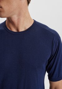 Short-sleeve crew-neck t-shirt in navy blue, made of soft knit fabric with a smooth texture and subtle stitching details on shoulders.