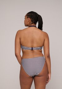 Pasiasty strój bikini w kolorze granatowym i białym, z topem na halterze z zapięciem z tyłu oraz dołem o średnim wzroście z boczną osłoną.