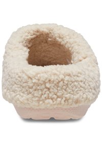Pantufla de color crema con una textura suave y esponjosa y un diseño de espalda abierta, que presenta una suela de goma para mayor agarre. Diseño minimalista con forma redondeada.