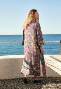 Długi kimono z wzorem w odcieniach różu, niebieskiego i złota. Posiada szerokie rękawy i luźny krój oraz miękką fakturę tkaniny.