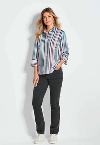 Gestreept overhemd met verticale strepen in blauw, roze en wit. Het heeft een kraag, driekwart mouwen en wordt gecombineerd met zwarte broek.