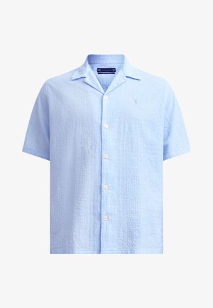 Korte mouwen, lichtblauw shirt met een textuurstof, kraag en vijf witte knopen. Kenmerkt zich door een subtiele geborduurde logo op de linker borst.