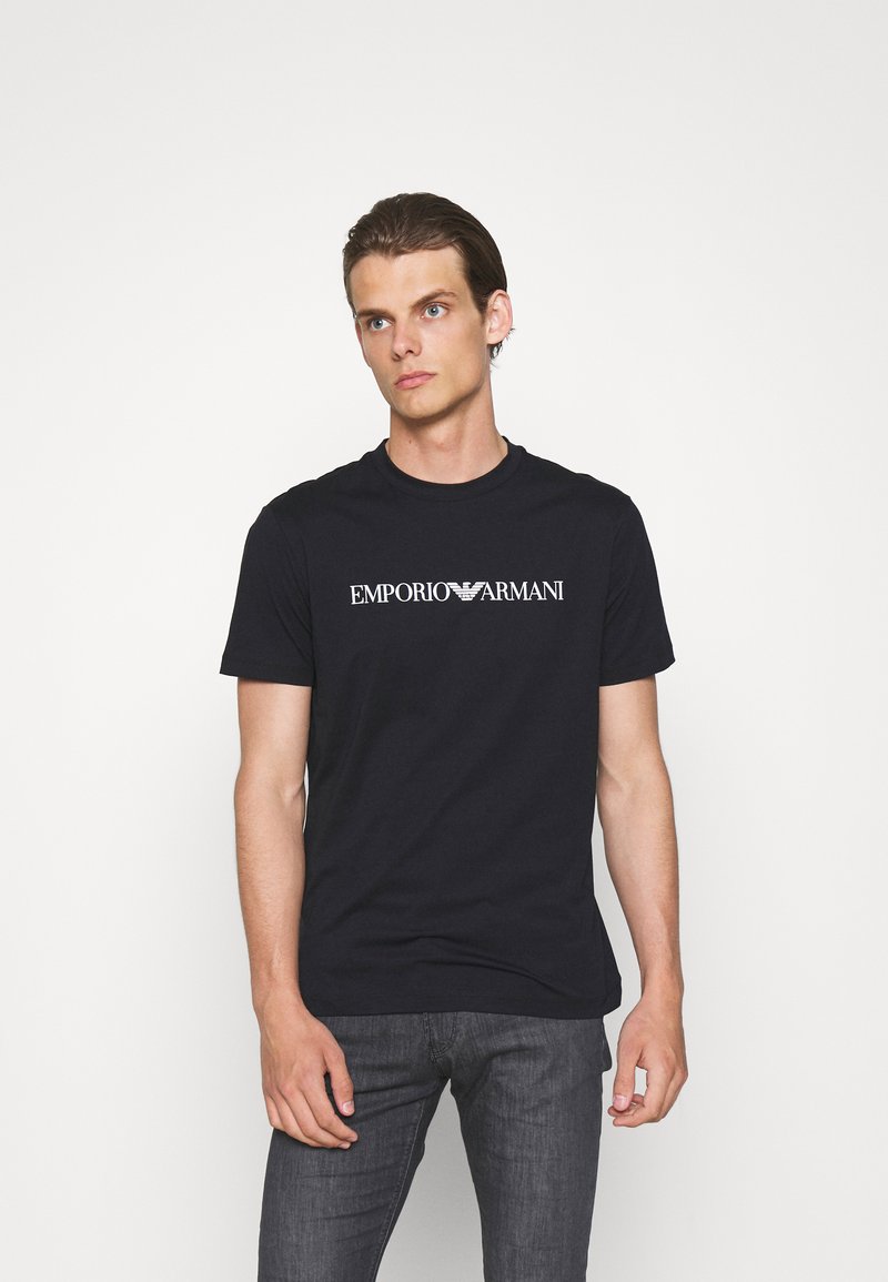 Black cotton t-shirt with a round neckline and short sleeves, featuring "EMPORIO ARMANI" logo in white on the front. Slim fit design.