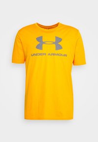 Žluté bavlněné tričko s šedým logem Under Armour a textem na přední straně. Klasický kulatý výstřih a krátké rukávy. Jednoduchý design.