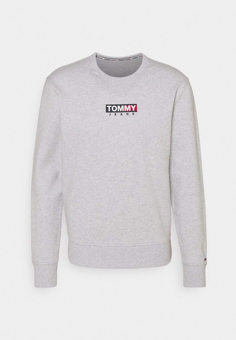 Sweat-shirt gris clair à col rond avec le logo "TOMMY JEANS" en noir, blanc et rouge centré sur la poitrine, poignets et ourlet côtelés.