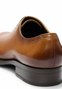 Brown leather dress shoe featuring a smooth texture, rounded toe, and a black rubber sole with subtle traction lines.