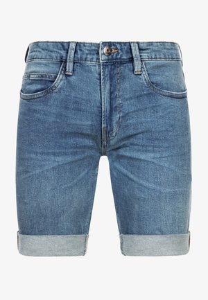 Biała bluza crewneck, szorty jeansowe z podwiniętymi mankietami oraz białe tenisówki. Casualowy strój charakteryzuje się teksturowaną tkaniną i luźnym krojem.
