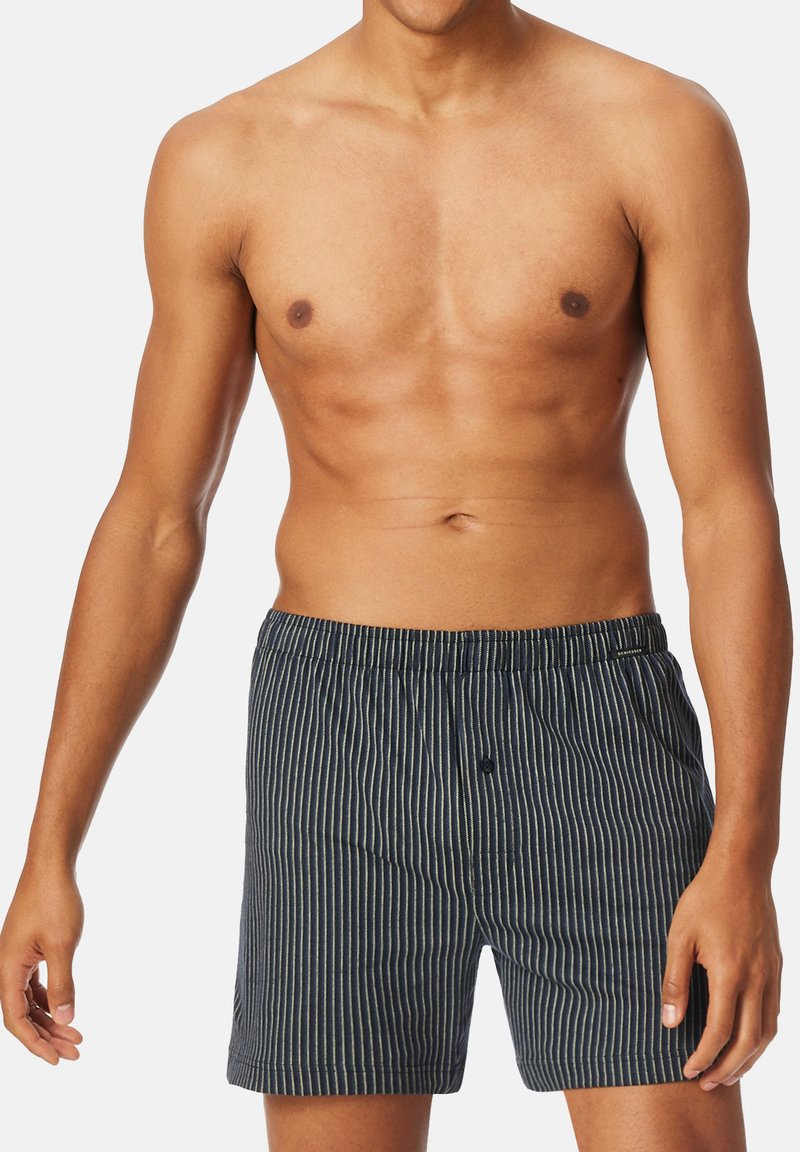 Randiga bomullsboxershorts i marinblått med vita vertikala linjer, elastiskt midjeband och en enkel knappstängning utformad för komfort.