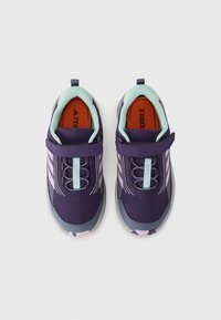 Des chaussures de sport violettes et grises au design épuré, dotées d'un dessus en maille, de lacets élastiques et d'une sangle à scratch.