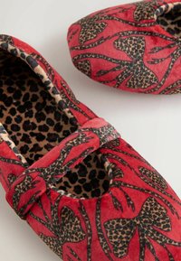 Piros papucs virágmintával, fekete kerettel és leopárdmintás béléssel. Elöl masnival díszítve. Puha tapintású.