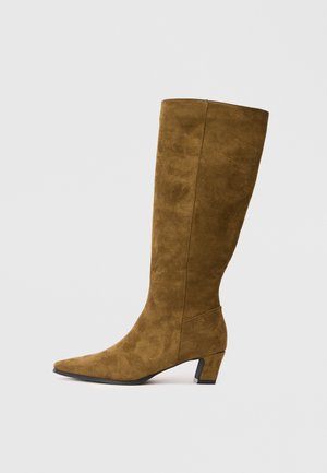 Brown suede knee-high boot with a pointed toe, low block heel, and smooth texture. Features a sleek, minimalistic design.