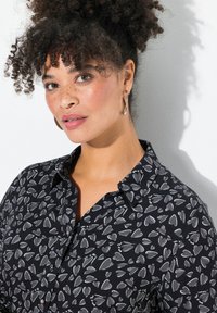 Schwarzes Button-Up-Hemd mit einem Herzmuster in Grautönen, klassischem Kragen und weicher Stofftextur, geeignet für die Freizeit.
