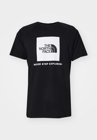 Camiseta de algodón negra con diseño de cuello redondo, que presenta un logo cuadrado blanco que incluye el texto "The North Face" y "Never Stop Exploring".