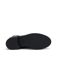 Suela de goma negra con agarre texturizado. La parte superior presenta cuero topo y una correa con hebilla plateada. Punta redondeada y diseño elegante.
