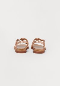 Sandale metalice de bronz cu talpă plată, având curele minime și închidere cu cataramă ajustabilă. Textură netedă și design deschis.