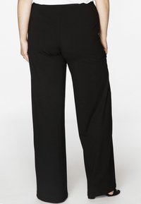 Schwarze weite Beinhosen aus weichem Stoff, mit einem elastischen Bund und einer glatten Textur, im bodenlangen Schnitt.
