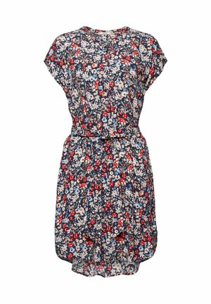 Vrouw draagt een korte, met riem gebloemde jurk met kapmouwen, met rode, witte en blauwe bloemen op een donkere achtergrond.