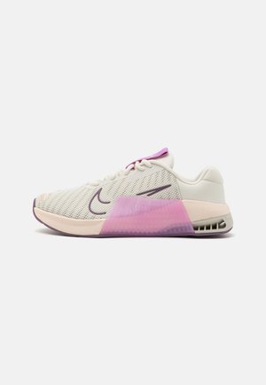 White and pink athletic sneaker with mesh upper, purple accents, visible heel air cushioning, and lace-up design, side profile view.