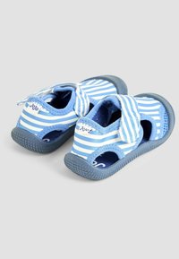 Zilas un balts svītrainas bērnu čības ar atvērtām malām, velcro siksniņu un strukturētām gumijas zolēm labākai saķerei. Zīmols redzams uz papēža.