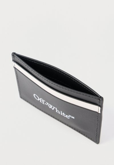 Črni usnjeni etuij za kartice z belim logotipom Off-White™ in vodoravno belo črto blizu zgornjega roba.