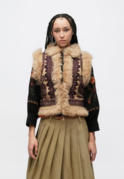 Faux fur vest with intricate purple and gold embroidery, featuring a high collar and a soft, textured finish, worn over a black blouse and skirt.