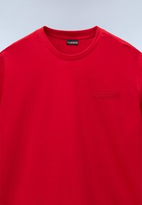 T-shirt rossa a maniche corte in cotone, con scollatura rotonda e un piccolo logo in rilievo sulla zona sinistra del petto.
