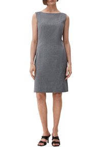 Hihaton harmaa mekko suoran leikkauksen kanssa, jossa on teksturoitu kangas, veneenasuinen pääntie ja polven pituinen siluetti. Yhdistetty mustiin sandaaleihin.