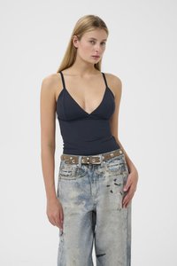 Sort badedragt med v-udskæring og tynde stropper, kombineret med slidte lyseblå baggy jeans og et brunt bælte med sølvnitter.