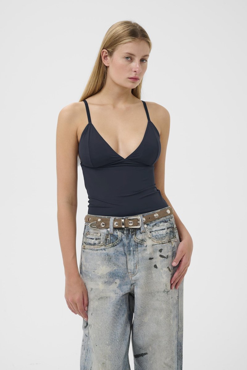 Sort badedragt med v-udskæring og tynde stropper, kombineret med slidte lyseblå baggy jeans og et brunt bælte med sølvnitter.