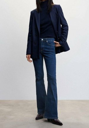 Laivansinis striped-puku, muotoon ommeltu poolopaita, leveälahkeiset tummansiniset farkut ja mustat teräväkärkiset nilkkasaappaat. Sileä kangas, räätälöity muotoilu.