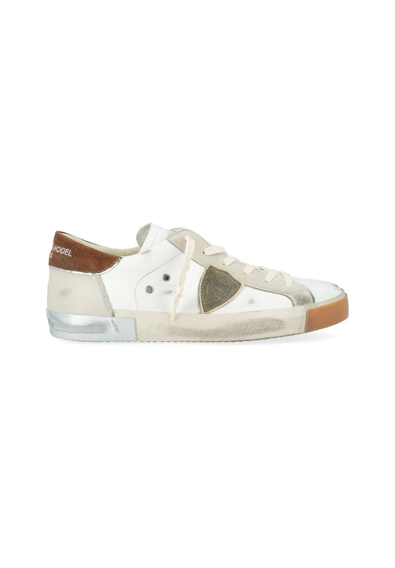 Sneaker bassa bianca con lacci beige, linguetta in suede marrone, suola in gomma usurata con segni di usura e un emblema a scudo sul lato.