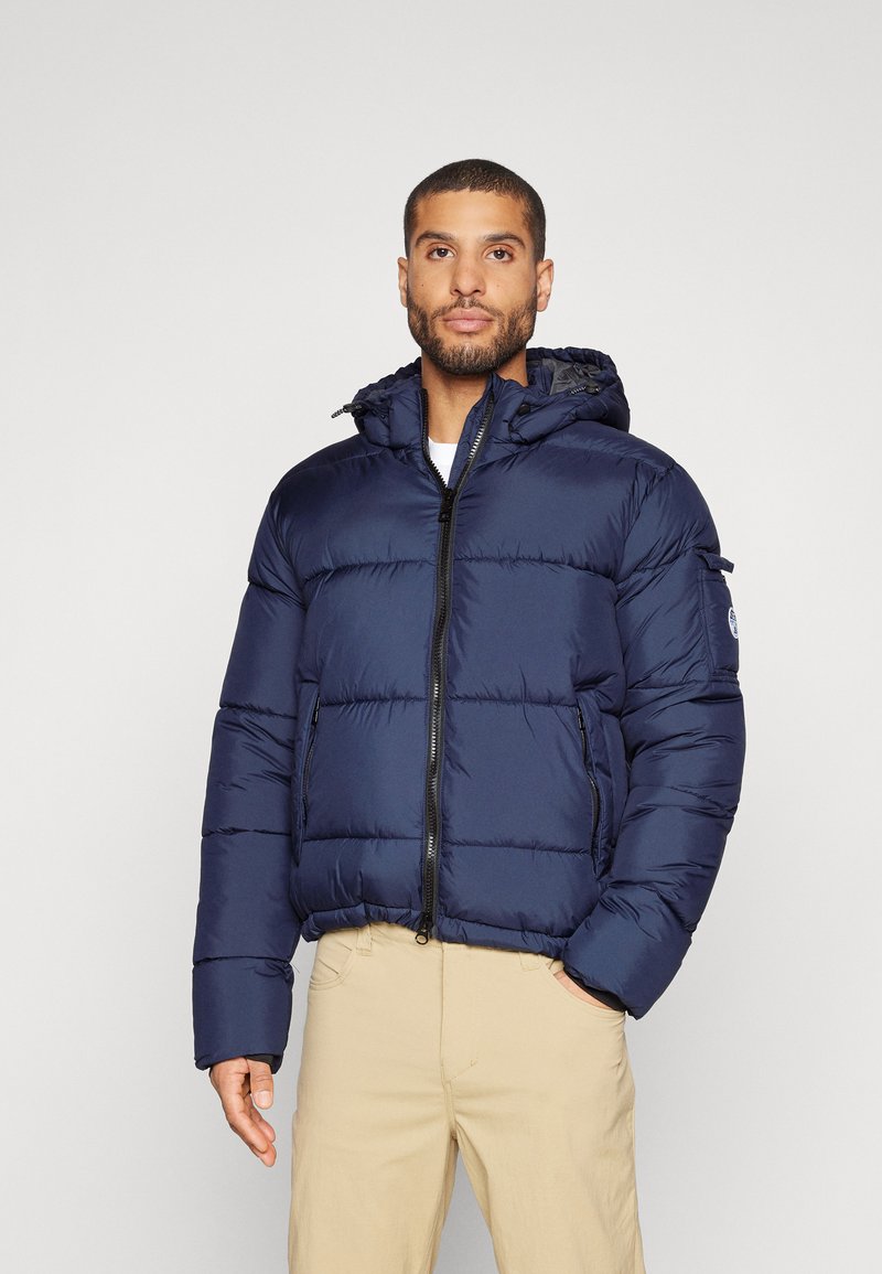 Marineblaue Daunenjacke mit Kapuze, mit einem durchgehenden Reißverschluss, horizontalen Nähten und zwei Seitentaschen. Hergestellt aus einem glänzenden, leichten Material.