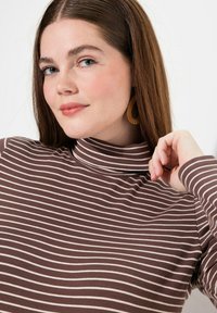 Maglione a collo alto a righe marroni e crema con maniche lunghe, caratterizzato da una texture di tessuto morbido e un design aderente.