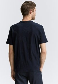 Donkerblauwe T-shirt met korte mouwen, voorzien van een gestructureerd palmbomenpatroon, ronde hals en een ontspannen pasvorm, gemaakt van zachte stof.