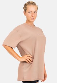 Overmaat t-shirt met korte mouwen in zachte stof in stofroze kleur, met een ronde halslijn en een subtiel geborduurd logo aan de voorkant. Zorgt voor een gladde textuur.