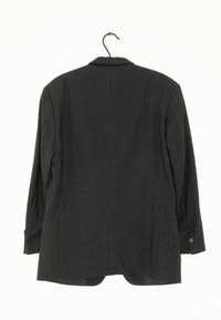 Mörkgrå blazer med långa ärmar, skräddarsydd design, enkel bakslits och knappdetaljer på ärmsluten. Hänger från en svart krok.